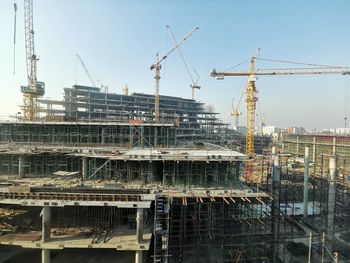 Cranes at construction site against sky in city