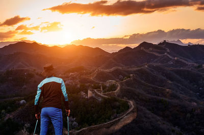 Rear view of man looking at mountains during sunset