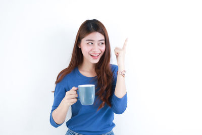 Young woman drinking coffee cup against white background