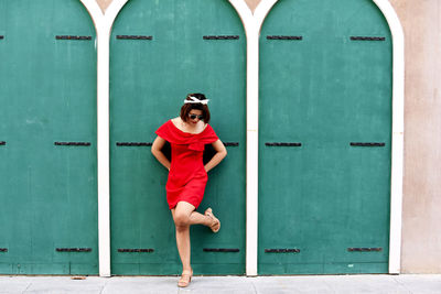Woman in red dress standing against wall