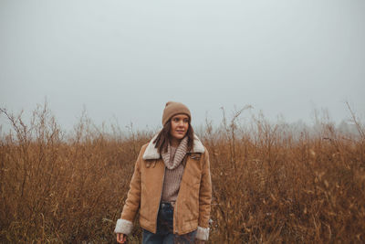 Portrait of mature woman standing on field against sky during winter