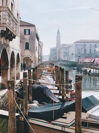 Boats moored at canal against buildings in city