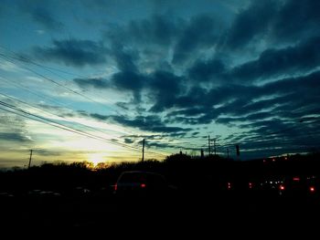 Cars on road against sky at sunset