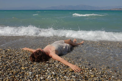 Boy on shore at beach against sky