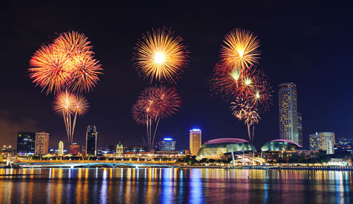 Firework display in city against sky at night