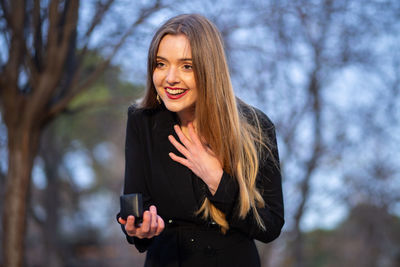 Low angle view of smiling young woman against sky