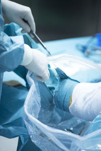 Cropped hand of doctor operating patient during knee surgery
