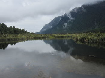 Scenic view of lake by mountains against sky