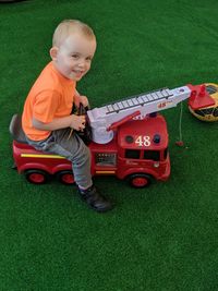 High angle portrait of cute boy playing with toy fire engine on turf