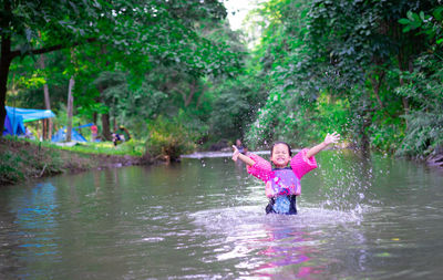 Girl with arms raised standing in lake