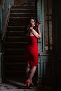 Full length portrait of woman standing by staircase