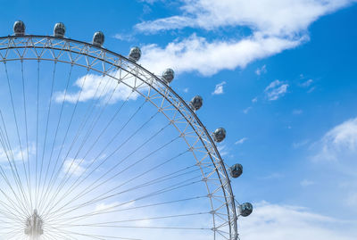 Low angle view of ferris wheel against cloudy sky