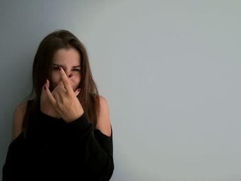 Young woman gesturing against gray wall