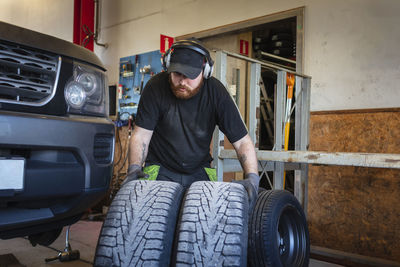 Mechanic in garage holding tires