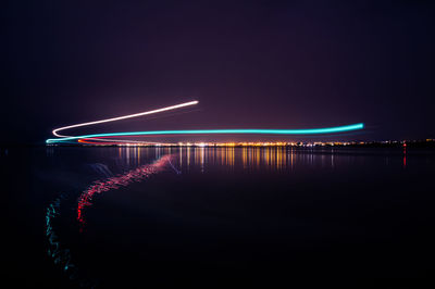 Illuminated bridge over river against sky at night