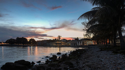 Scenic view of sea by buildings against sky during sunset