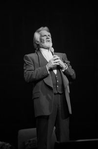 Full length of a man holding camera over black background