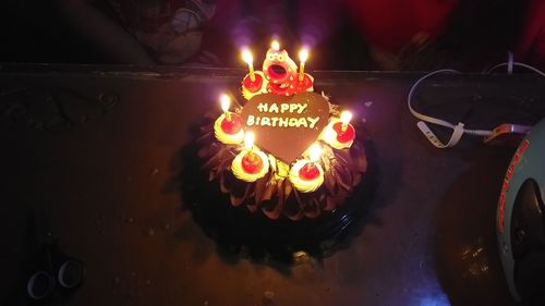 High angle view of illuminated candles on birthday cake