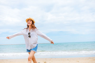 Woman standing at beach against sky