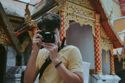 Front view point of young man traveller and photographer in temple yellow theme