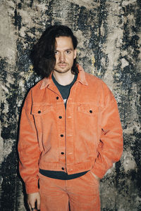 Portrait of young man standing against wall