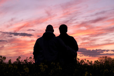 Rear view of silhouette friends against orange sky
