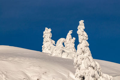 Snow covered land against clear blue sky