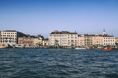 View of buildings by sea against clear sky