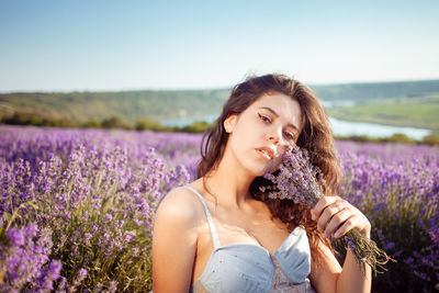A beautiful young girl against the sunset and a beautiful sky in a lavender field. 