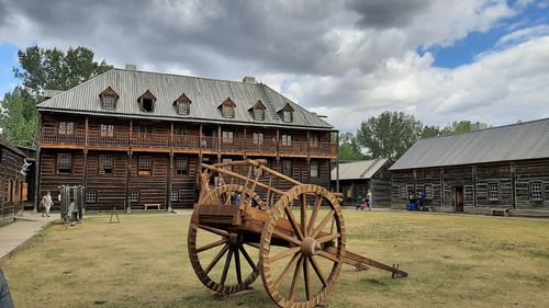 Traditional windmill on field by building against sky