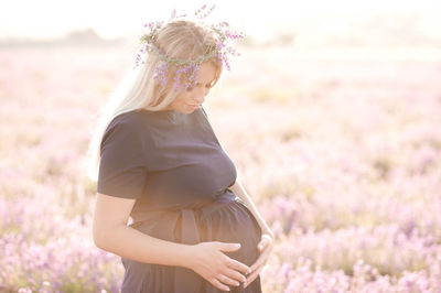 Smiling pregnant woman standing on field