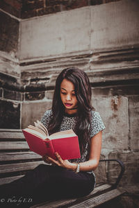 Young woman sitting on book