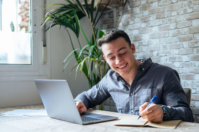 Portrait of young man using laptop at office