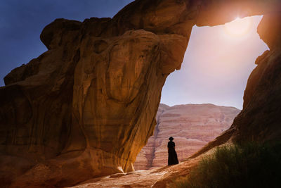 Rear view of woman standing on rock against mountain