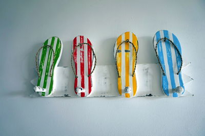 Close-up of colorful hooks in flip-flop shaped on white wall