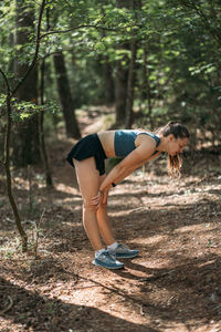 Young woman in sportswear tired and resting in the forest after working out. trail running and sport
