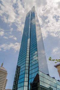 Low angle view of modern buildings against cloudy sky