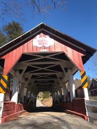 Low angle view of bridge amidst buildings against clear blue sky