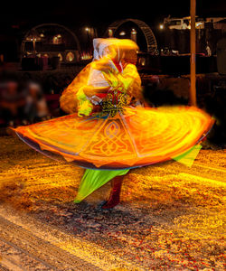 Midsection of woman with umbrella standing at night