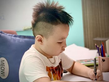 Portrait of boy sitting on table at home