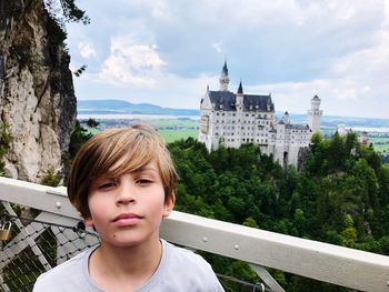 Portrait of boy by railing against sky