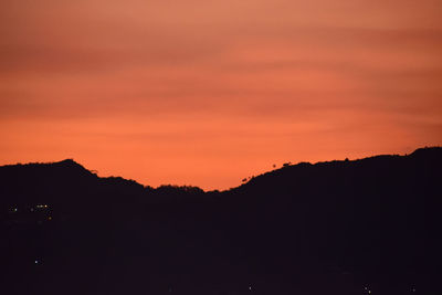 Scenic view of silhouette mountains against orange sky