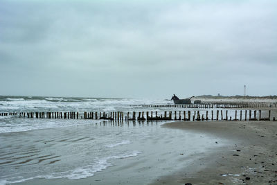 Wooden posts on beach against sky