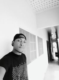 Portrait of young man standing against wall at home