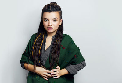 Portrait of young woman standing against white background