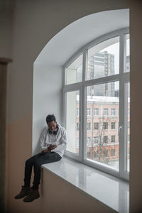 Young male african american student sitting on a windowsill in an educational institution