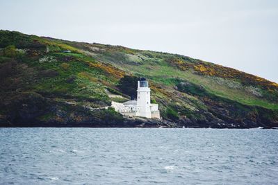 Lighthouse by sea against sky