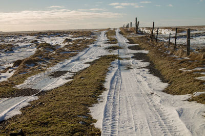 Tire tracks on road along snow covered land