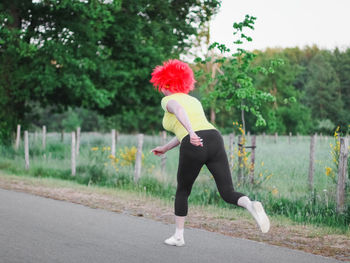 Caucasian woman runner in a belgian flag wig runs in a funny marathon.