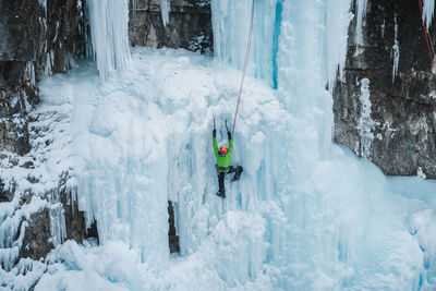 Male ice-climber scaling a massive and treacherous ice wall. 